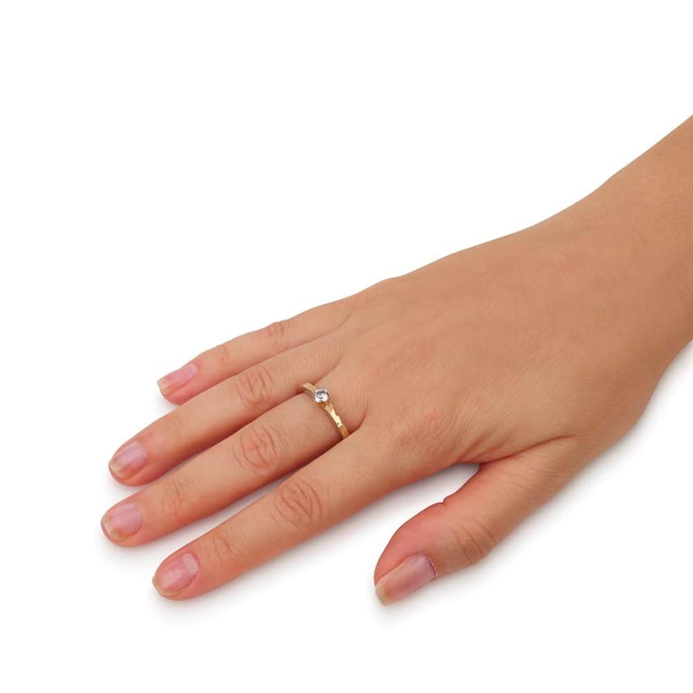 Woman wearing a delicate two-tone sterling silver and hammered 9K gold ring with a round CZ stone