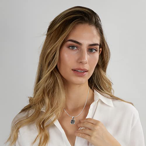 A woman with blonde-highlighted hair wearing a silver chain necklace with a Hoshen Twelve Tribes necklace featuring blue and white stones, paired with a white collared shirt against a light gray background.
