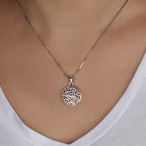 A silver pendant necklace with Hebrew letters and  an intricate cutout design, shown worn on a model's neck over a white V-neck top.