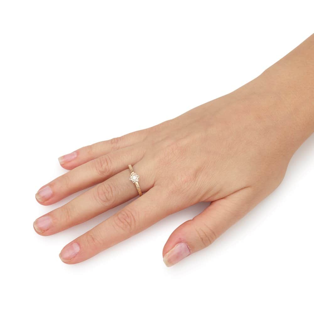 Close-up of a woman's hand wearing a slim two-tone Magen David ring with hammered gold detail and sparkling CZ center